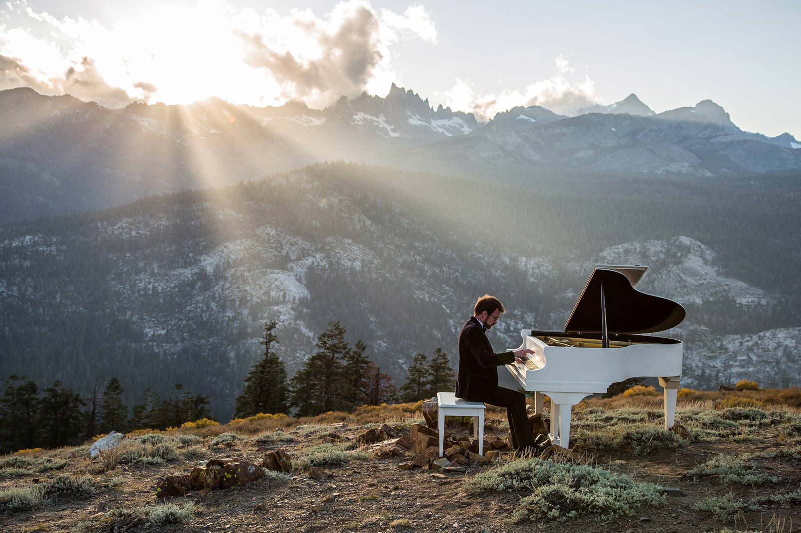 Julian Jenson playing a grand piano on a mountain.